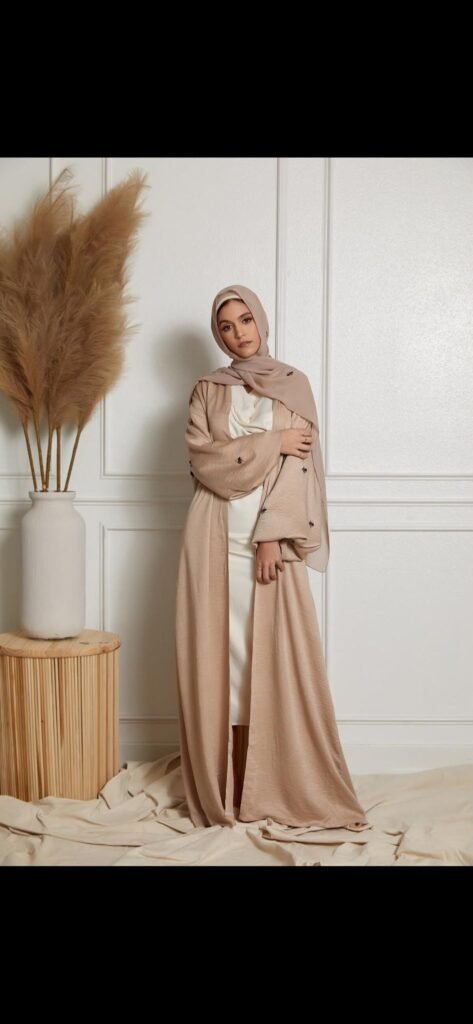 Modèle portant une abaya beige brodée, décor de pampas et bois clair